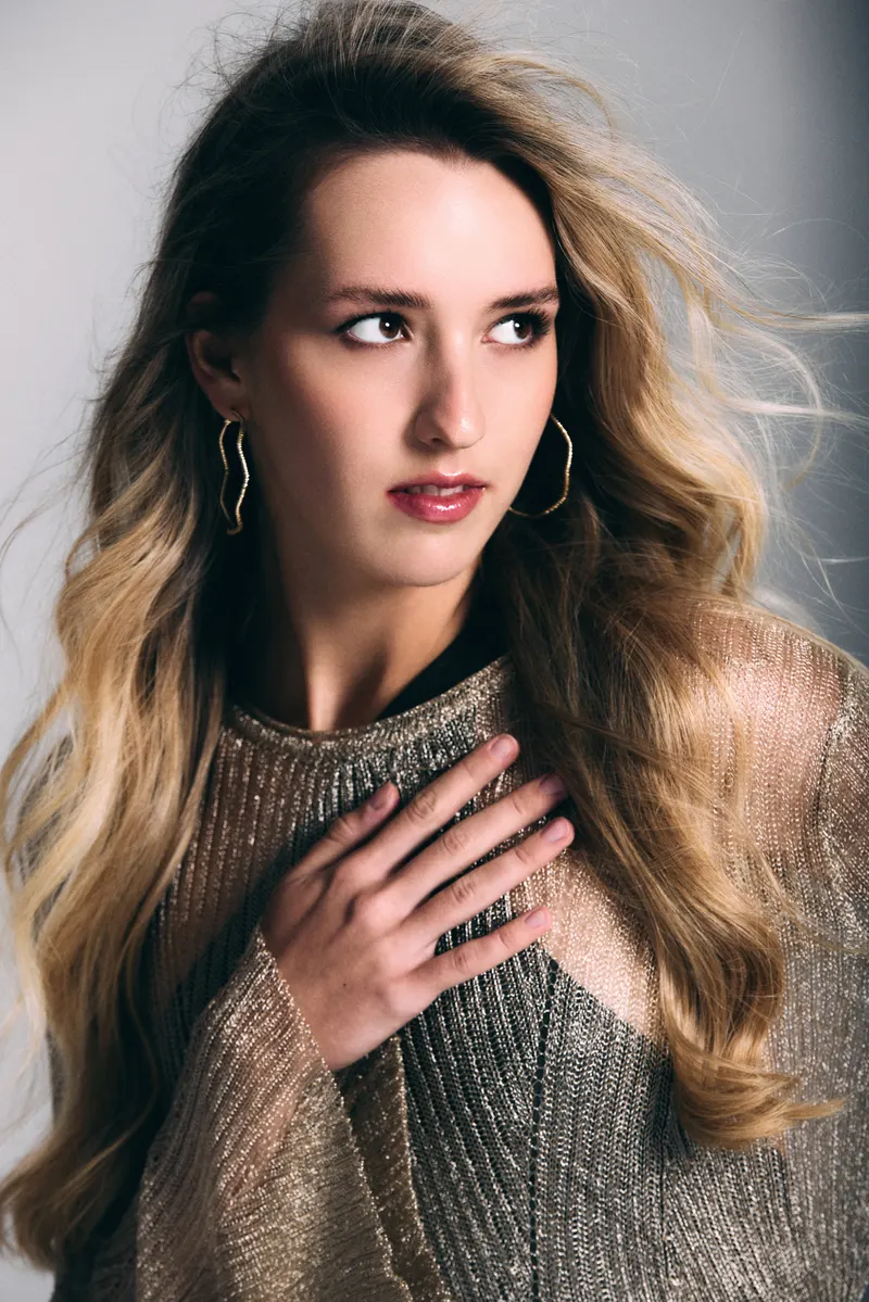 Portrait of Lisa in metallic knit, hand at her collarbone