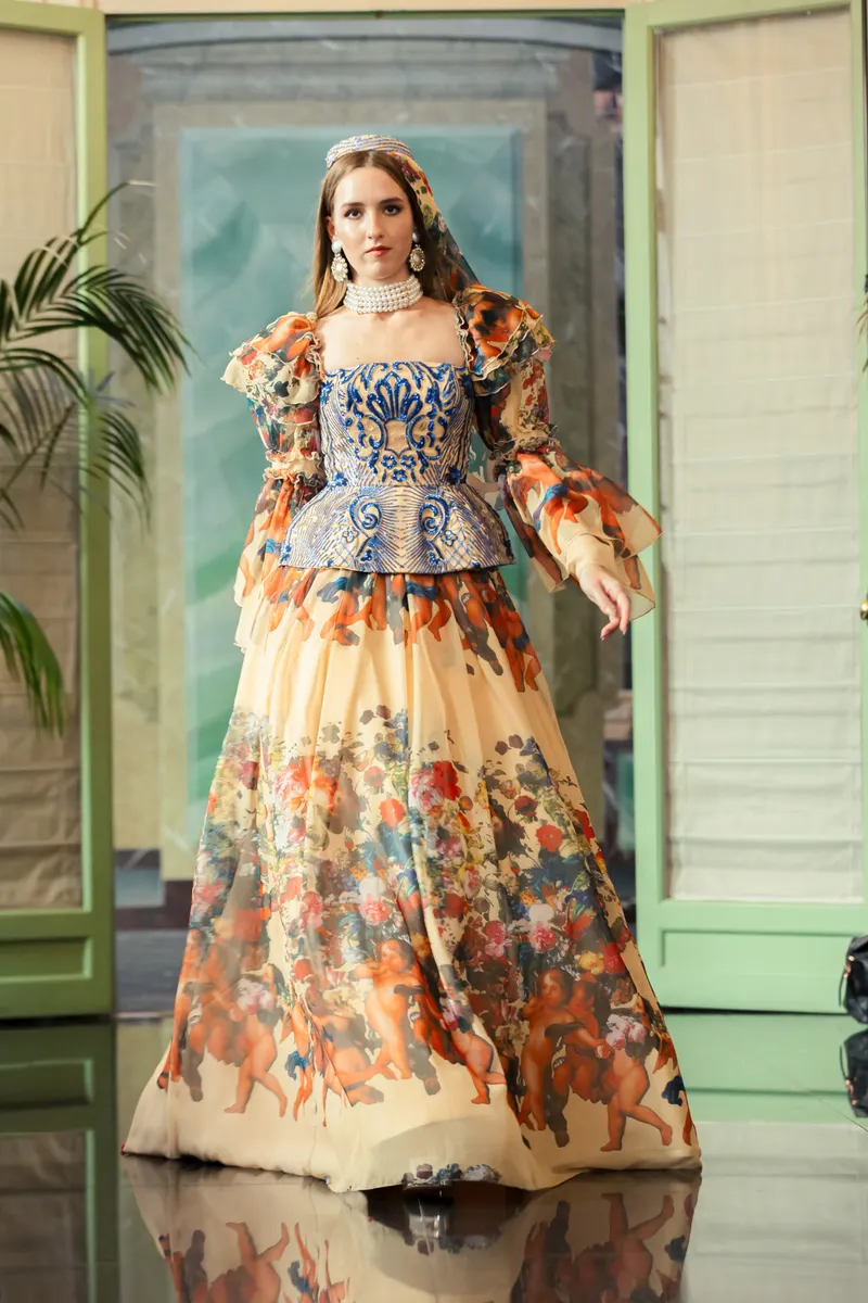 Lisa on a salon runway in a floral printed gown with a blue embroidered bodice