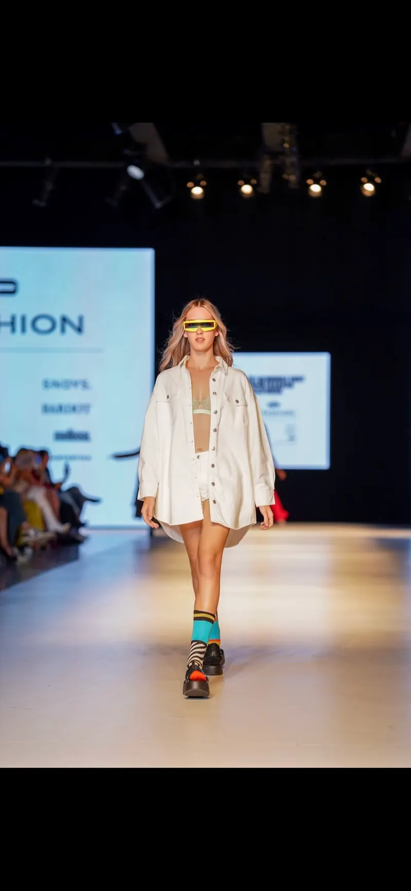 Lisa on a fashion week runway in an oversized white jacket and shorts