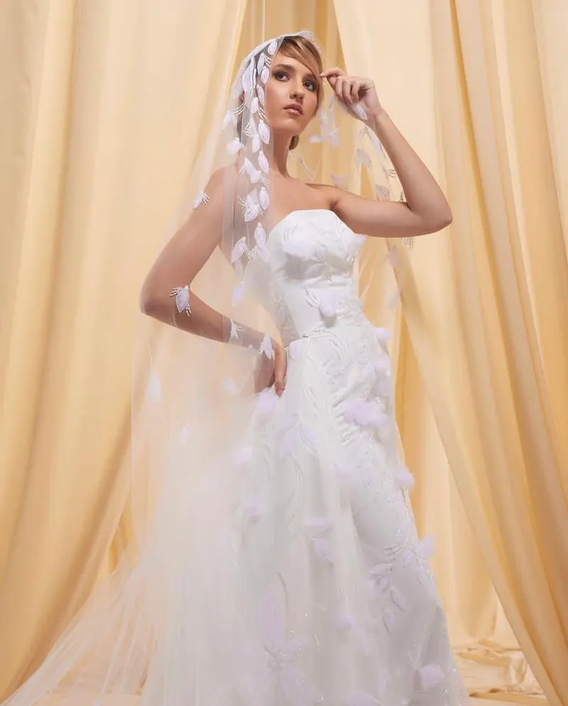 Lisa in a strapless bridal gown and long veil against cream drapes