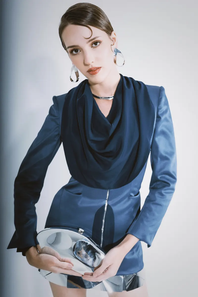 Lisa in a navy draped jacket with a silver clutch